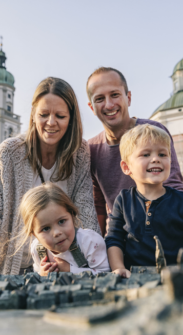 Two adults and two children are looking at the town model of Kempten