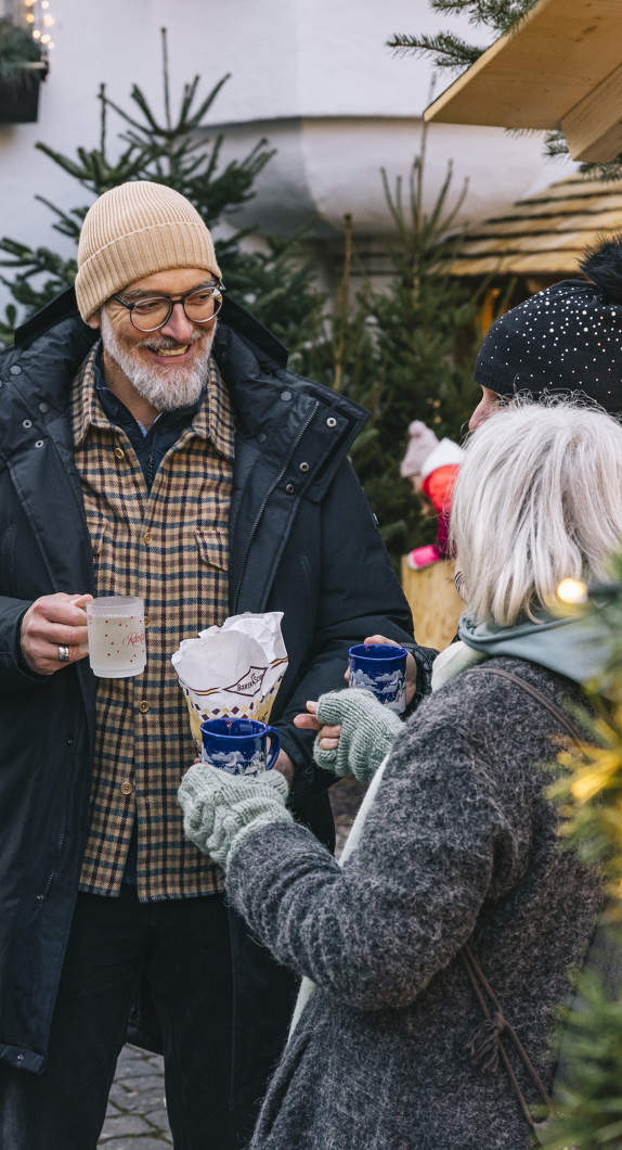 Menschen mit Glühweintassen auf dem Weihnachtsmarkt