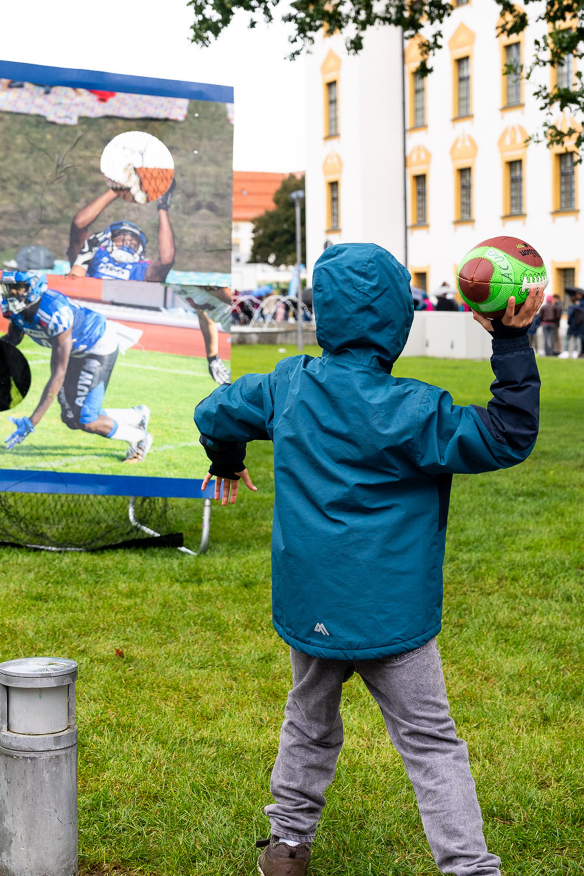 Kind wirdt einen Football in eine Torwand mit Löchern - Copyright: Niko Spettmann